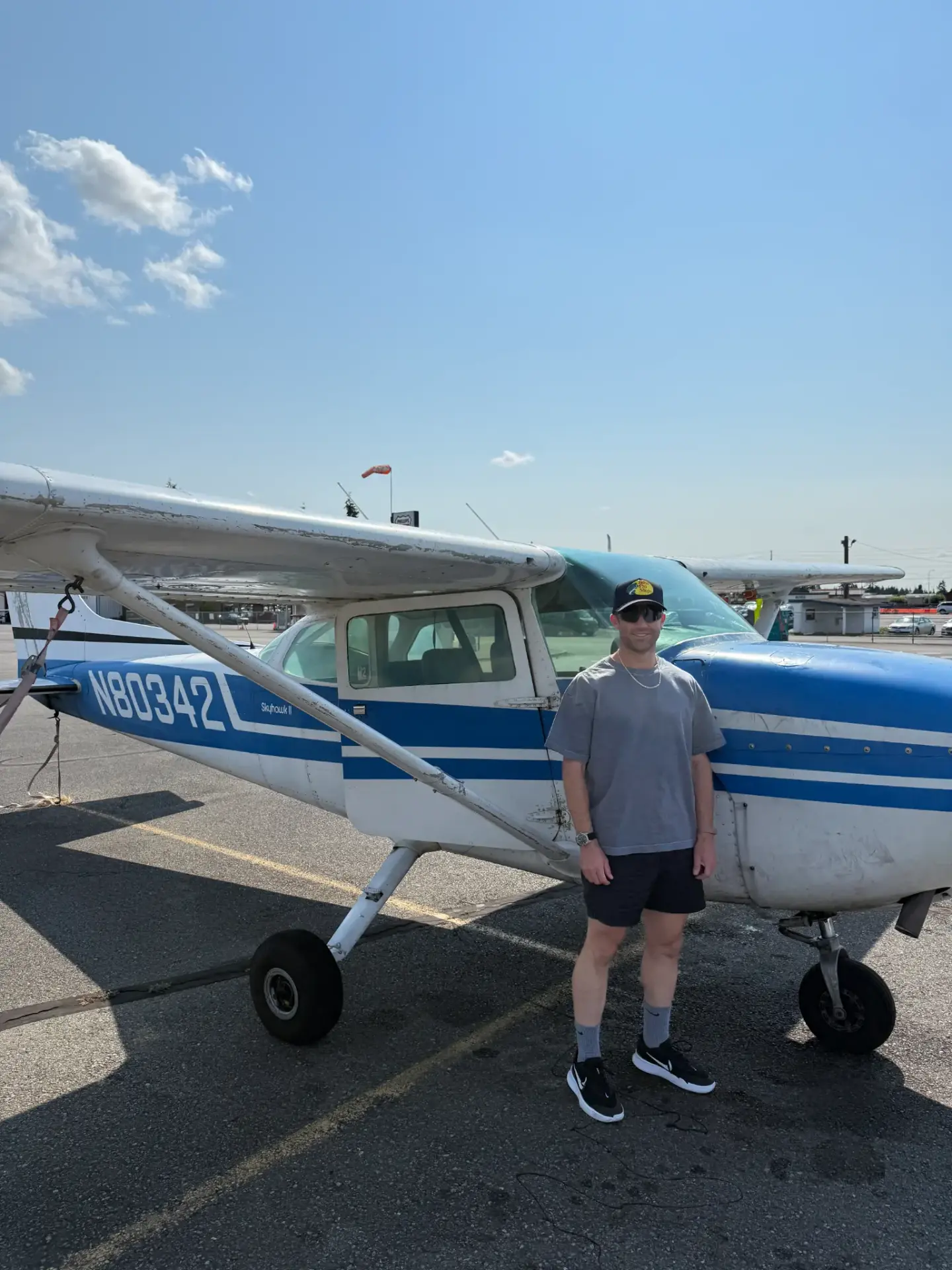 Ryan standing beside a blue and white Cessna Skyhawk on the ramp on a clear day